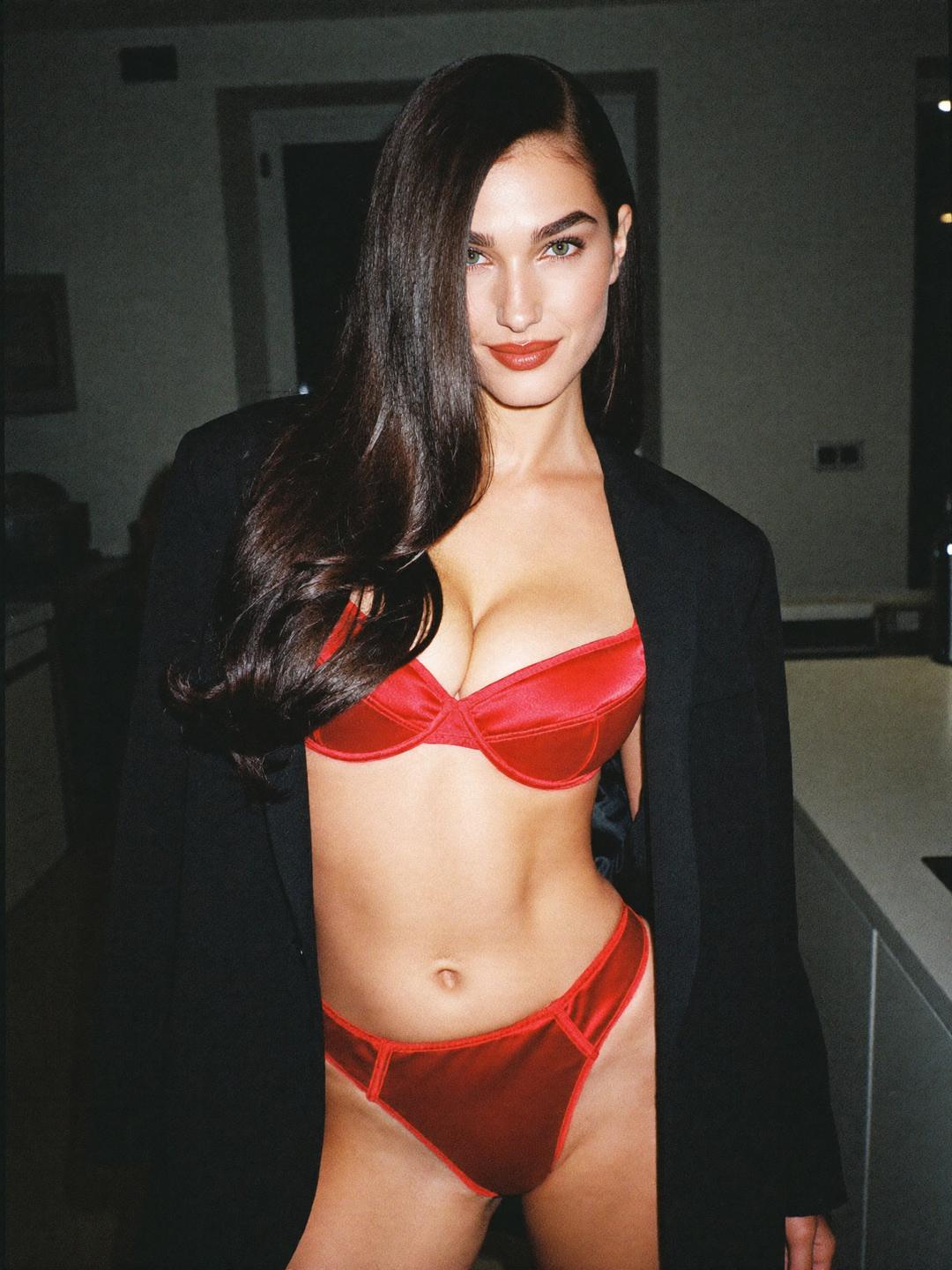Ava in red satin lingerie and a black blazer in her apartment kitchen at night