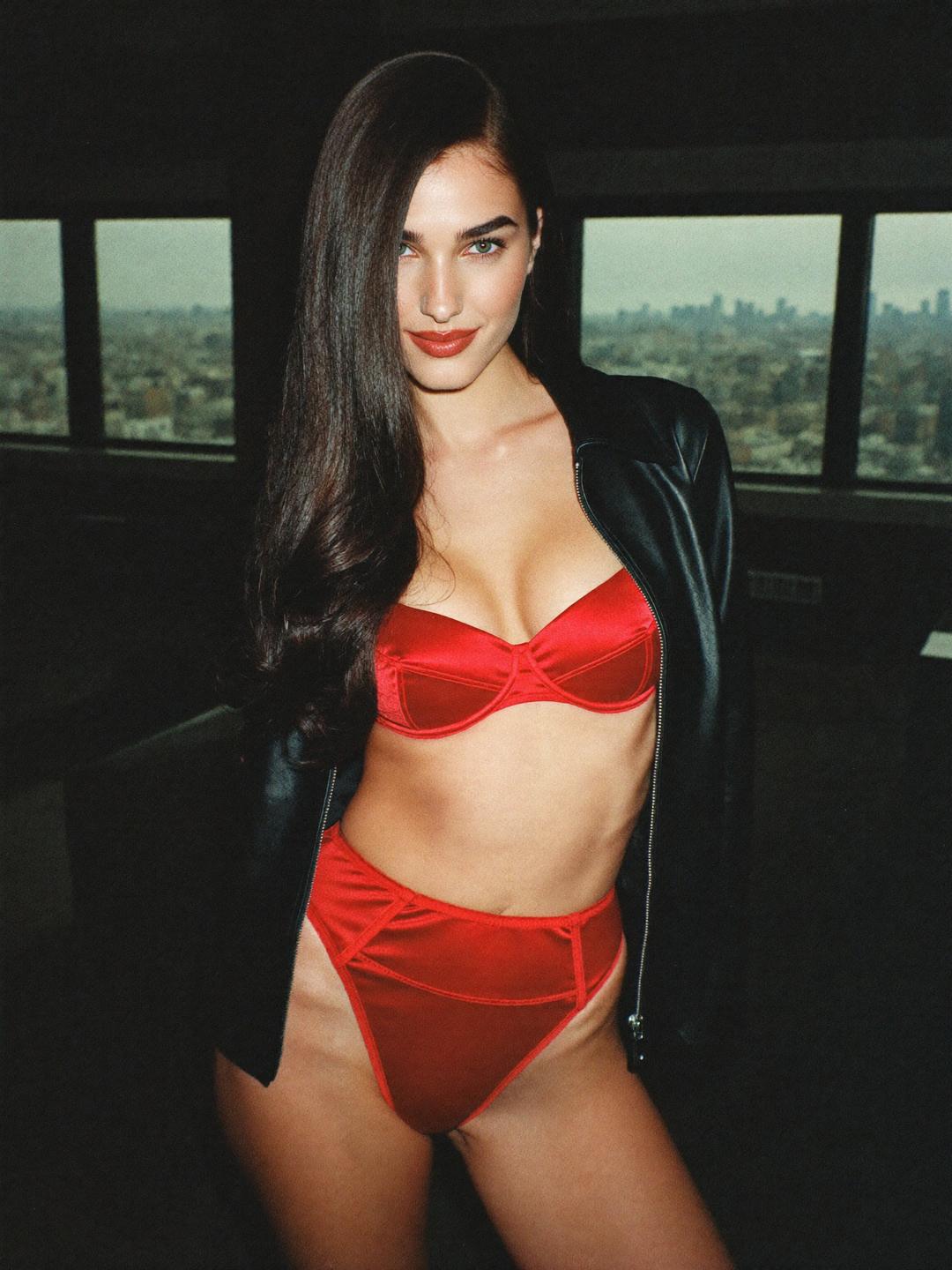 Ava in red satin lingerie under a black leather jacket in a New York loft