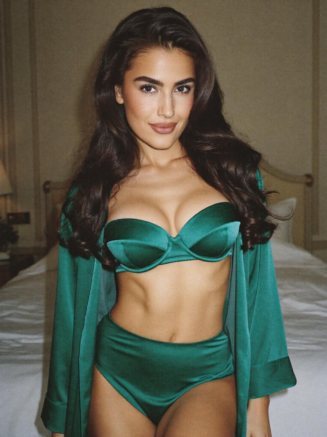 Giulia in emerald satin lingerie and a silk robe in an elegant bedroom