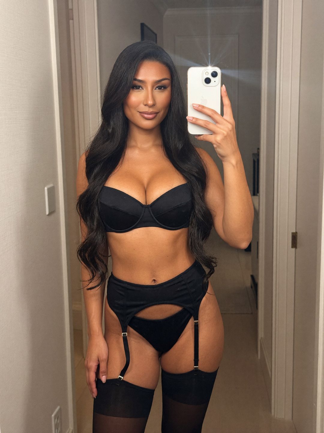 Reina with long straight jet-black hair, taking a phone mirror selfie, wearing a black garter set, in a minimalist Tokyo hotel room.