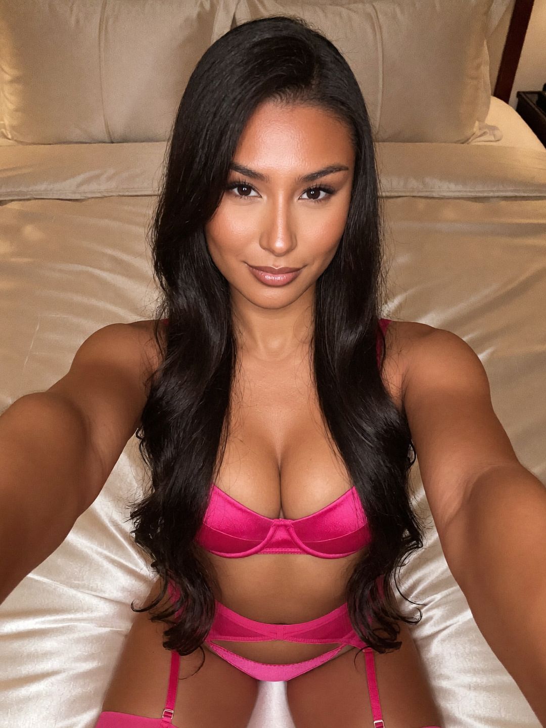 Reina with long straight jet-black hair, kneeling on a satin bed, taking a selfie from above, wearing a hot pink suspender belt, in a Tokyo bedroom with champagne satin sheets.